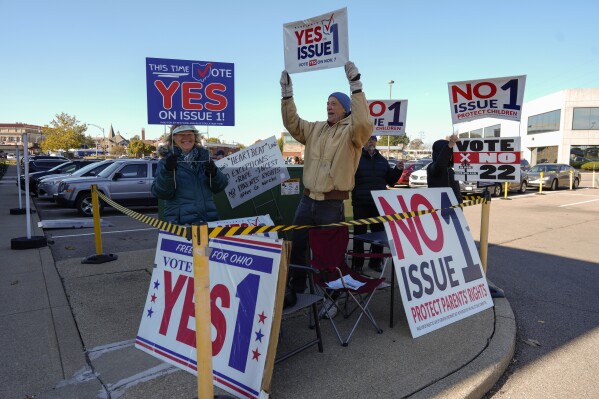 People gather in the parking lot of the Hamilton County Board of Elections as people arrive for early in-person voting in Cincinnati, Thursday, Nov. 2, 2023. They urge a vote for or against the measure known as Issue 1. Issue 1 is the only abortion question on any state ballot this year. (AP Photo/Carolyn Kaster)