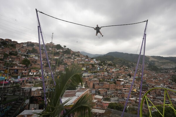 A tourist rides a bungee jump in the Comuna 13 neighborhood of Medellin, Colombia, Friday, Feb. 2, 2024. Once a battleground for fighting among drug cartels, leftist guerrillas, military forces, and government-linked paramilitary groups, the area is now a tourist attraction. (AP Photo/Fernando Vergara)