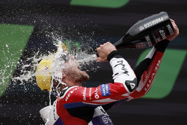 Britain's Jake Dixon celebrates on the podium after winning the Moto 2 race of the Catalunya Motorcycle Grand Prix at the Catalunya racetrack in Montmelo, just outside of Barcelona, Spain, Sunday, Sept. 3, 2023. (AP Photo/Joan Monfort)