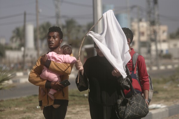 A woman holds up a stick with a shirt attached as a white flag to prevent being shot, as Palestinians flee Gaza City to the southern Gaza Strip on Salah al-Din street in Bureij, Nov. 7, 2023. (AP Photo/Mohammed Dahman)