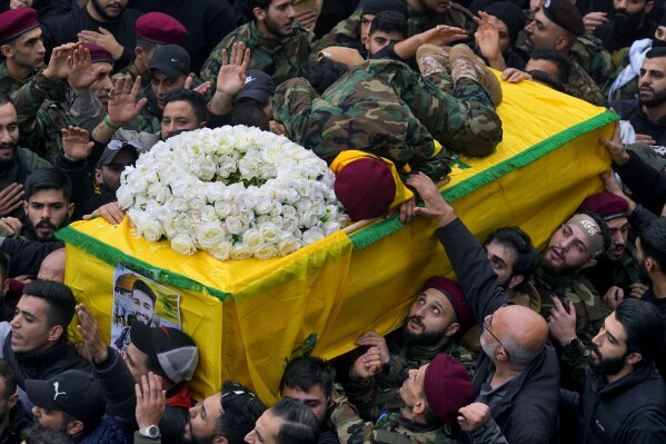 Hussein, brother of Hezbollah fighter Ali Hassan al-Atat, who was killed by an Israeli strike, lies on top of his brother's coffin during his funeral procession in the southern Beirut suburb of Dahiyeh, Lebanon, Thursday, Dec. 7, 2023. (AP Photo/Bilal Hussein)