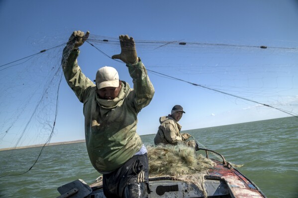 Serzhan Seitbenbetov, left, and Omirserik Ibragimov fish in a part of the Aral Sea with water, far away from their village Tastubek, outside Aralsk, Kazakhstan, Sunday, July 1, 2023. (AP Photo/Ebrahim Noroozi)