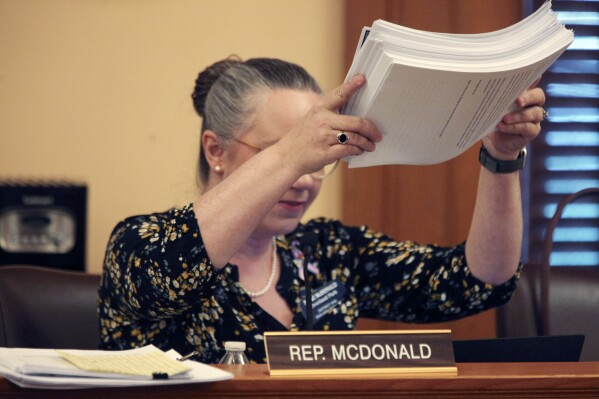 Kansas state Rep. Nikki McDonald, D-Olathe, shows off a stack of printed testimony in favor of expanding the Medicaid program in Kansas during a House Health and Human Services Committee discussion, Thursday, March 21, 2024, at the Statehouse in Topeka, Kan. The committee has blocked Democratic Gov. Laura Kelly's expansion plan. (AP Photo/John Hanna)