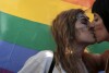 FILE - Two women kiss in front of a rainbow flag, the symbol of the gay rights movement, during the Gay Pride parade in central Athens, Saturday, June 14, 2014. Greece’s center-right government is speeding up its timetable to legalize same-sex marriage despite growing opposition from the powerful Orthodox Church. Government officials said on Wednesday, Jan. 24, 2024, that draft legislation would be put to a vote by mid-February. (AP Photo/Petros Giannakouris, File)
