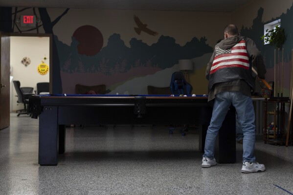 A client plays pool on a quiet afternoon at FOCUS Recovery and Wellness Community Center in Findlay, Ohio, Friday, Oct. 20, 2023. FOCUS offers free support and resources to anyone impacted by mental health, addiction, or trauma issues. The community center hosts 12-step meetings, serves meals and helps connect people with other services. (AP Photo/Carolyn Kaster)