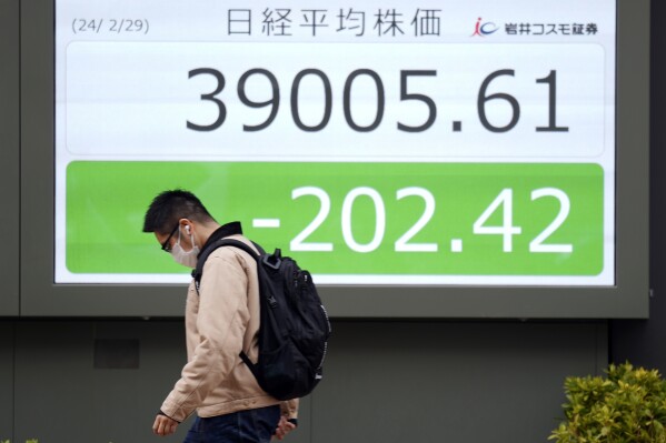 Un hombre camina frente a un tablero de acciones electrónico que muestra el índice Nikkei 225 de Japón en una firma de valores en Tokio, el jueves 29 de febrero de 2024.  Las acciones estuvieron mixtas en Asia el jueves después de un día deslucido en Wall Street, donde una liquidación de acciones tecnológicas debilitó los índices de referencia.  (Foto AP/Eugene Hoshiko)