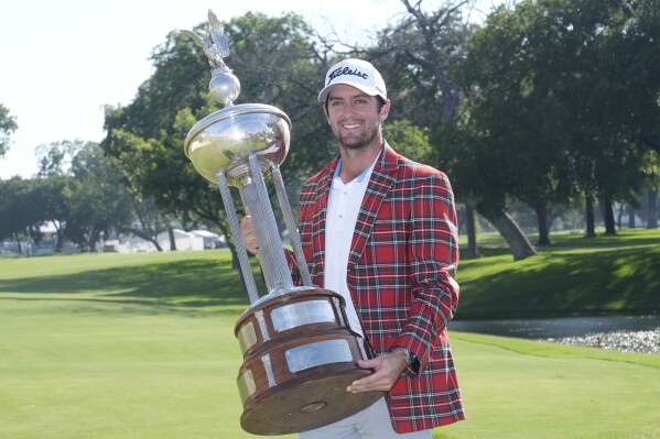 Davis Riley poses with the winner's trophy at the Charles Schwab Challenge golf tournament at Colonial Country Club in Fort Worth, Texas, Sunday, May 26, 2024. (AP Photo/LM Otero
