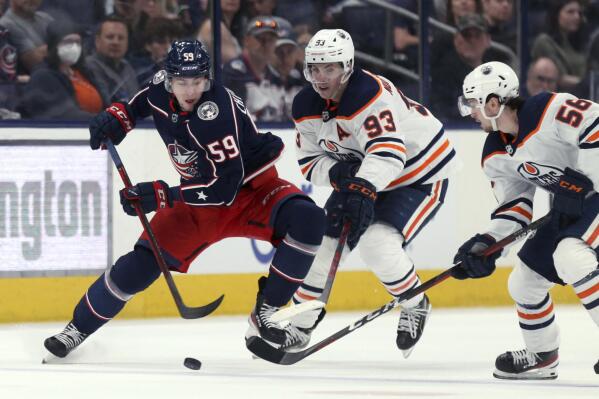 Columbus Blue Jackets forward Yegor Chinakhov, left, chases the puck in front of Edmonton Oilers forward Ryan Nugent-Hopkins, center, and forward Kailer Yamamoto during the second period an NHL hockey game in Columbus, Ohio, Sunday, April 24, 2022. (AP Photo/Paul Vernon)