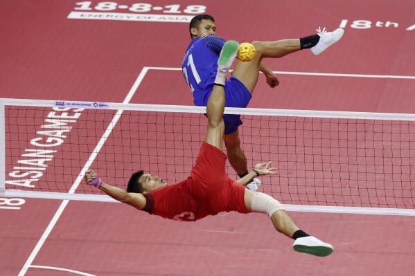 FILE - Lao's Noum Souvannalith, left, kicks a ball against Thailand's Jirasak Pakbuangoen during the men's sepak takraw team doubles final match at the 18th Asian Games in Palembang, Indonesia, on Aug. 25, 2018. The Asian Games open officially on Saturday, Sept. 23, 2023. (AP Photo/Vincent Thian, File)