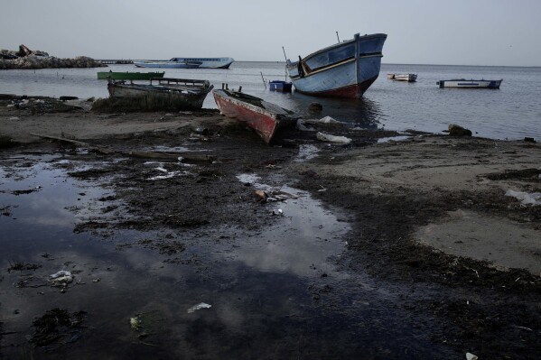 FILE - Wrecked boats that carried migrants are seen in the coastal city of Monastir, Tunisia, on April 16, 2018. Tens of thousands of migrants are trapped in an increasingly violent limbo in camps In Tunisia, blocked from reaching Europe but too poor to go home, and facing backlash from local residents. (AP Photo/Nariman El-Mofty, File)