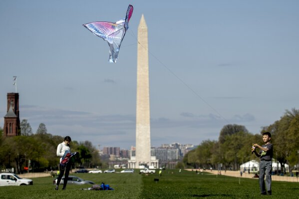 In this April 6, 2020 photo, the Washington Monument is visible behind a boy as he flies a kite on the National Mall in Washington. The warmer weather is bringing increased violations of social distance guidelines in the nation’s capital, even as health officials predict that Washington could become one of the next U.S. hot spots in the coronavirus pandemic. (AP Photo/Andrew Harnik)