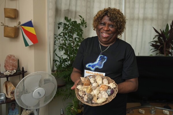 Chagossian Bernadette Dugasse shows sea shells from the Chagos Islands during an interview with The Associated Press, at her home in London, Tuesday, March 25, 2025. (AP Photo/Kin Cheung)