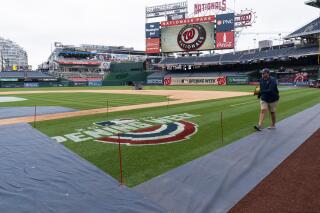 A member of the grounds crew ropes off the on field logo before baseball workouts at Nationals Park, Wednesday, April 6, 2022, in Washington. The Washington Nationals and the New York Mets are scheduled to play on opening day, Thursday. (AP Photo/Alex Brandon)