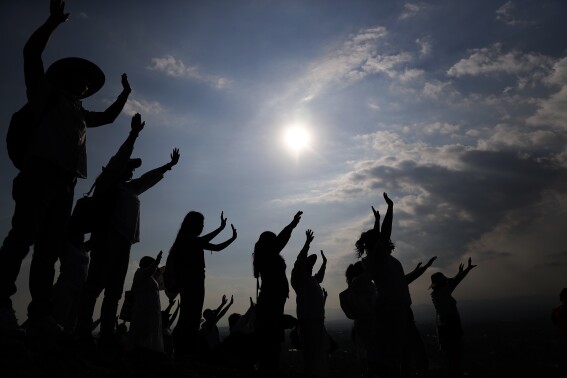 FILE - Visitors hold their hands out to receive the sun's energy as they celebrate the Spring equinox atop the Pyramid of the Sun in Teotihuacan, Mexico, Thursday, March 21, 2019. Spring gets its official start Tuesday, March 19, 2024, in the Northern Hemisphere. On the equinoxes, the Earth's axis and orbit line up so both hemispheres get the same amount of sunlight. (AP Photo/Marco Ugarte, File)
