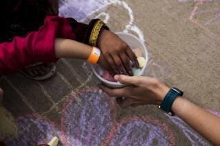 In this Aug. 31 , 2021, photo provided by the U.S. Army, Afghan children take a piece of chalk at a children's activity event held by non-governmental charities at Fort McCoy in Wisconsin. U.S. officials are looking into reports that in the frantic evacuation of desperate Afghans from Kabul, older men were admitted together with young girls they claimed as “brides” or otherwise sexually abused. One internal document seen by The Associated Press says the State Department has sought “urgent guidance” from other agencies after purported child brides were brought to Fort McCoy. (Spc. Rhianna Ballenger/U.S. Army via AP)