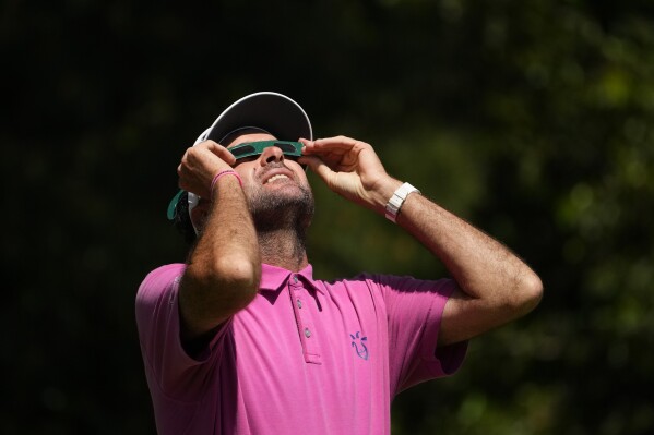Bubba Watson looks up at the sun during an solar eclipse while standing on the first hole during a practice round in preparation for the Masters golf tournament at Augusta National Golf Club Monday, April 8, 2024, in Augusta, Ga. (AP Photo/Matt Slocum)