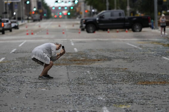 Cheryl Herpich takes a photograph of a downtown building with blown out windows in the aftermath of a severe thunderstorm Friday, May 17, 2024, in Houston. Thunderstorms pummeled southeastern Texas on Thursday killing at least four people, blowing out windows in high-rise buildings and knocking out power to more than 900,000 homes and businesses in the Houston area. (Ǻ Photo/David J. Phillip)