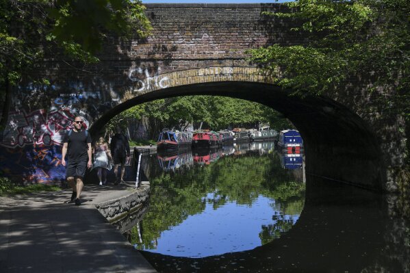 People walk on the footpath alongside Regent's Canal, as the lockdown continues due to the coronavirus outbreak, in London, Sunday, April 26, 2020. The public have been asked to self isolate, keeping distant from others to limit the spread of the contagious COVID-19 coronavirus.(AP Photo/Alberto Pezzali)