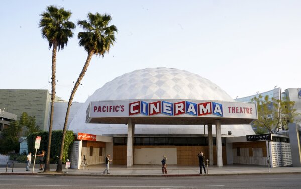 Bystanders gather outside the Cinerama Dome movie theater, Monday, April 12, 2021, in Los Angeles. Pacific Theaters, which operates some 300 screens in California, including the beloved ArcLight th...
