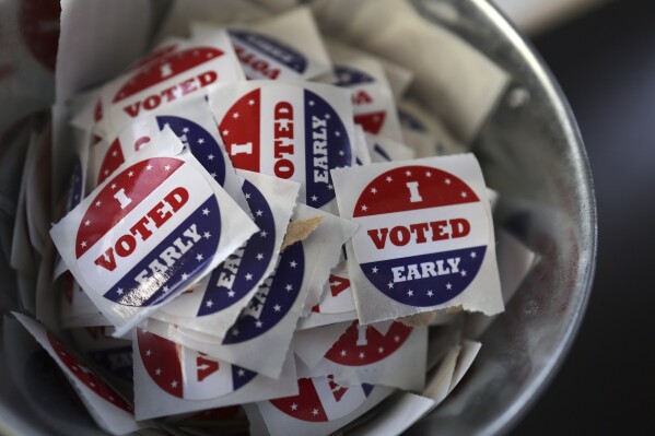 FILE "- I Voted Early" stickers sit in a bucket by the ballot box at the City of Minneapolis early voting center, Thursday, Sept. 19, 2024, in St. Paul, Minn. (AP Photo/Adam Bettcher, File)