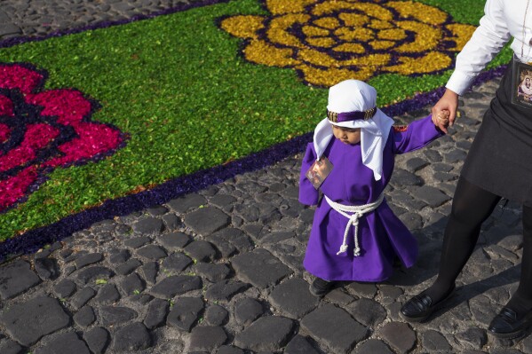 A child dressed as a cucurucho walks past a sawdust carpet at the start of Holy Week in Antigua, Guatemala, on Palm Sunday, March 24, 2024. (AP Photo/Moises Castillo)