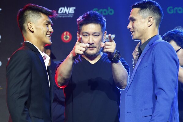 FILE - In this Tuesday, July 30, 2019 file photo, Chatri Sityodtong, Chair and CEO of ONE Championship, center, gestures as Reece McLaren, right, of Australia and Danny Kingad, left, of the Philippines face off during the media presentation for this Friday's ONE Championship mixed martial arts fight dubbed: Dawn of Heroes, in suburban Pasay city south of Manila, Philippines. One Championship definitely will return to action this summer during this unprecedented public health crisis, Chatri Sityodtong told The Associated Press on Wednesday June 10, 2020, but the promotion has not finalized a date or location for its first fights. (AP Photo/Bullit Marquez, File)