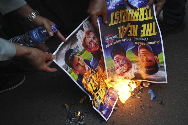 Muslim protesters burn posters during a rally outside the Swedish Embassy in Jakarta, Indonesia, Monday, Jan. 30, 2023. Hundreds of Indonesian Muslims marched to the heavily guarded Swedish Embassy in the country's capital on Monday to denounce the recent desecration of Islam's holy book by far-right activists in Sweden and the Netherlands. (AP Photo/Tatan Syuflana)