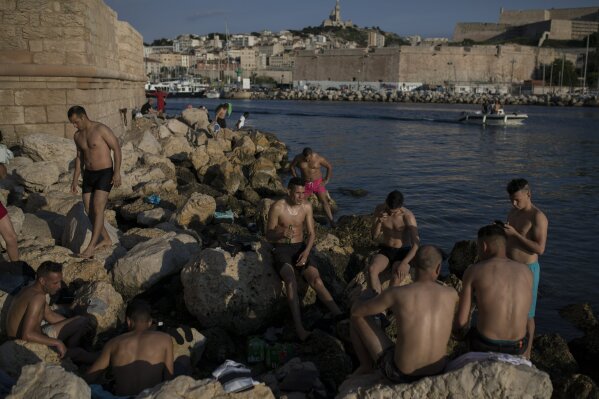 Sunbathers enjoy the sunset at the entrance to Marseille's Old Port in southern France, Tuesday, May 26, 2020 as France gradually lifts its COVID-19 lockdown. (AP Photo/Daniel Cole)