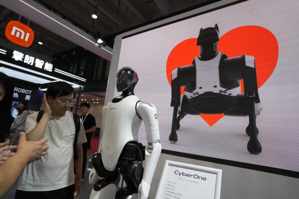 A human like cyborg and an image of a robot dog is displayed at the Xiaomi booth at the annual World Robot Conference at the Beijing Etrong International Exhibition and Convention Center in Beijing, Wednesday, Aug. 16, 2023. (AP Photo/Ng Han Guan)