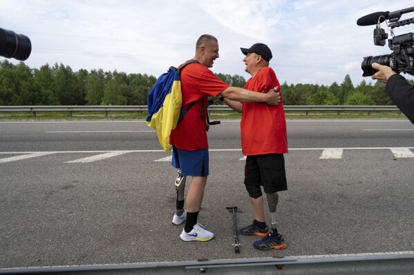 Ukrainian war veterans from 2014, Serhii Khrapko, right, and Oleksandr Shvetsov hug each other as they finish a 120-kilometer (75-mile) walk to raise money for medical equipment in honor of their comrades wounded in Russia's war against their homeland, in Yuriv, Zhytomyr region, Ukraine, on Friday, May 19, 2023. They raised 3.1 million hryvnias ($84,000), short just the 500,000 hryvnias ($14,000) needed to purchase a new gastroscope for Ukraine's National Military Medical Clinical Center. (APPhoto/Roman Hrytsyna)