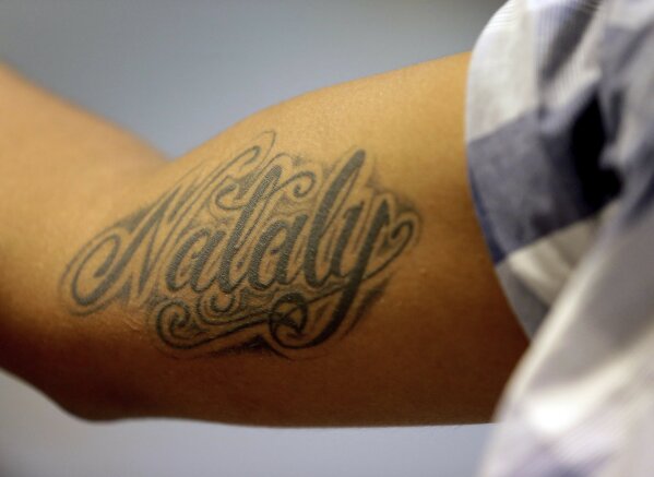 
              CORRECTS AGE OF NATALY TO 5 YEARS OLD, NOT 8-Wilson Romero, from Honduras, shows his tattoo of his 5-year-old daughter Nataly's name at the Annunciation House, Tuesday, June 26, 2018, in El Paso, Texas. Romero, along with 31 other parents separated from their children, are staying at the home. Romero was told his daughter is being held in Arizona. If the Trump administration has any hope of complying with a judge's order to reunite thousands of migrant children and parents within 30 days, it's going to have to clear away the red tape and confusion many immigrants have encountered so far. (AP Photo/Matt York)
            
