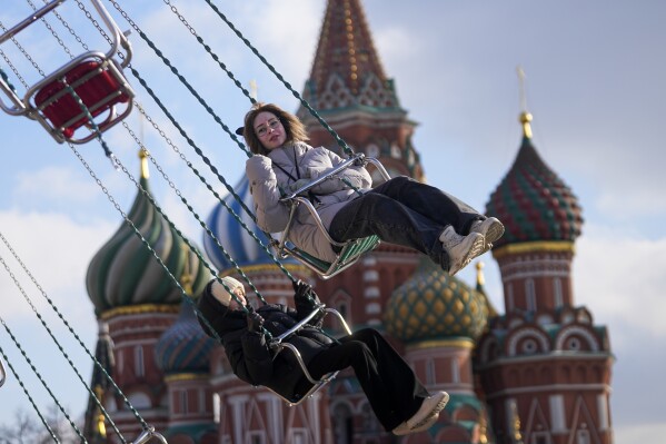 People ride a chain carousel at the Red Square with the St. Basil's in the background in Moscow, Russia, Tuesday, Feb. 18, 2025. (AP Photo/Pavel Bednyakov)