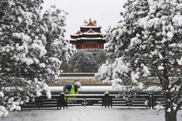 In this photo released by Xinhua News Agency, a worker clears snow near the Turret of the Forbidden City following a snowfall in Beijing, Wednesday, Feb. 21, 2024. Heavy snow has blanketed northern and central China, disrupting traffic and forcing schools to cancel classes. (Ju Huanzong/Xinhua via AP)