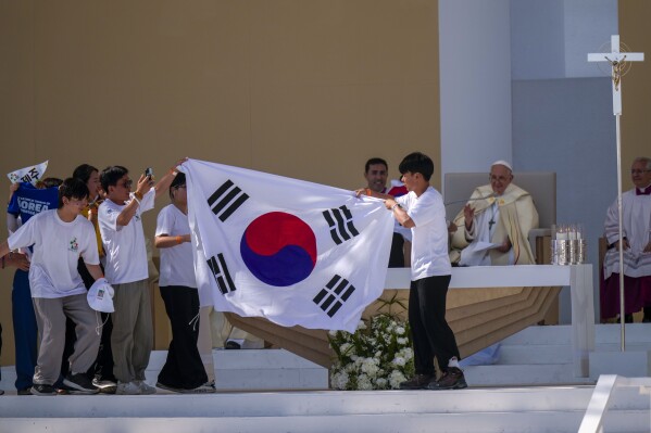 Young pilgrims from South Korea celebrate with their national flag and with Pope Francis after he announced that the next World Youth Day, will be in Seoul, South Korea in 2027, at the end of a mass at Parque Tejo in Lisbon, Sunday, Aug. 6, 2023. An estimated 1.5 million young people filled the parque on Saturday for Pope Francis' World Youth Day vigil, braving scorching heat to secure a spot for the evening prayer and to camp out overnight for his final farewell Mass on Sunday morning. (AP Photo/Francisco Seco)