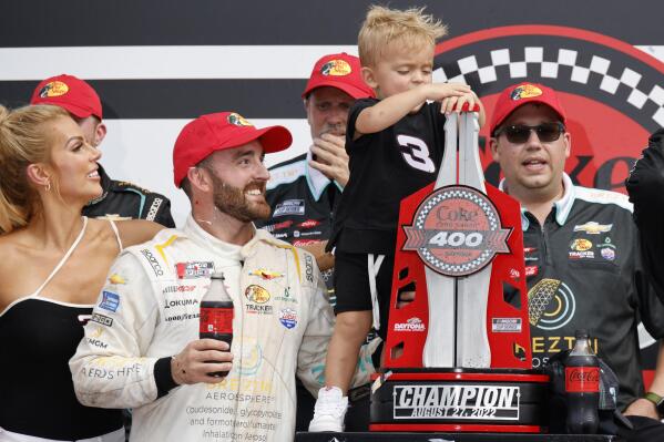 Austin Dillon and his wife Whitney Dillon, left, watch as their son, Ace, plays with the championship trophy in Victory Lane after Dillon won a NASCAR Cup Series auto race at Daytona International Speedway, Sunday, Aug. 28, 2022, in Daytona Beach, Fla. (AP Photo/Terry Renna)