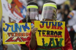 FILE- Indigenous persons known as Lumad wearing protective masks and traditional dress hold slogans as they join a rally against the anti-terror law at the University of the Philippines in Manila, Philippines, July 4, 2020. The Philippine Supreme Court on Thursday Dec. 9, 2021, largely upheld the legality of an anti-terrorism law that opponents fear could threaten democracy and muzzle dissent, but struck down a provision preventing street protests, activism and labor strikes from being branded as terrorism by authorities. (AP Photo/Aaron Favila, File)