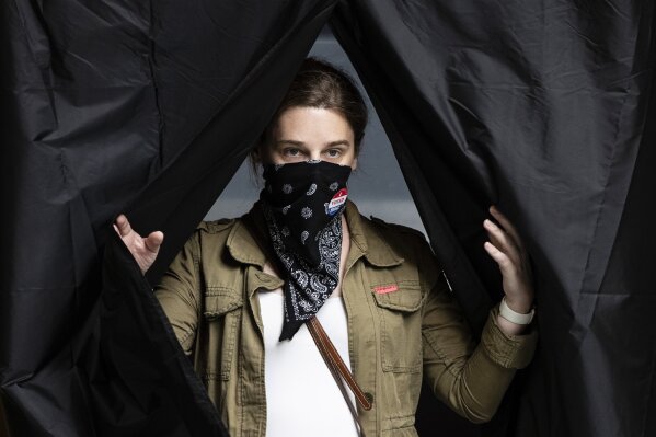 Jenn McCullough, wearing a protective face mask as a precaution against the coronavirus, steps from the voting booth after casting her ballot in the Pennsylvania primary at the Kimmel Center in Philadelphia, Tuesday, June 2, 2020. (AP Photo/Matt Rourke)
