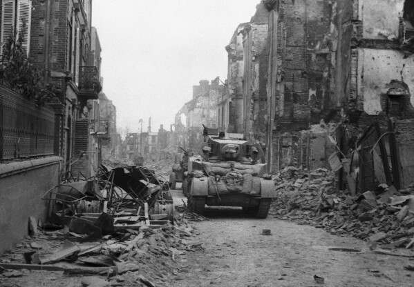 FILE - A British tank makes its way along a street, with the battle still in progress, as the city is still fringed with Nazi guns which continually lob shells into the street, in St. Lo, Normandy, France on June 20, 1944. (AP Photo, File)