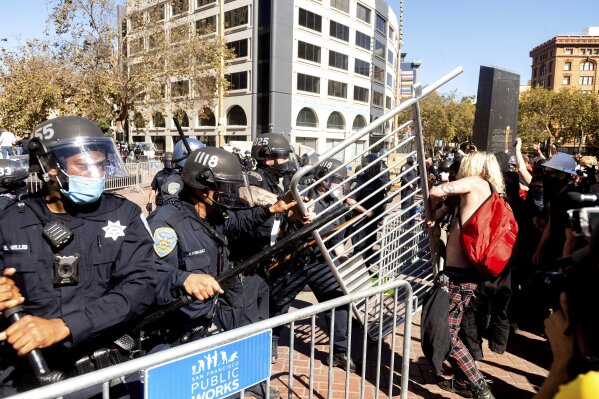 Police officers to to hold off counter-protesters as conservative activists stage a free speech rally in San Francisco on Saturday, Oct. 17, 2020. About a dozen pro-Trump demonstrators were met by several hundred counter-protesters as they tried to rally. (AP Photo/Noah Berger)