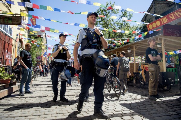 FILE - Police patrol Pusher Street in at Christiania, Copenhagen, Friday, May 25, 2018, after the street reopened after having been closed for three days. Copenhagen’s mayor is urging urged foreigners not to buy weed in a the city's Christiania neighborhood known for its flourishing hashish trade where a 30-year-old man was killed by shots last month and four people injured. (Nils Meilvang/Ritzau Scanpix via AP, File)
