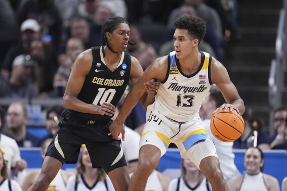Marquette's Oso Ighodaro (13) dribbles as Colorado's Cody Williams (10) defends during the second half of a second-round college basketball game in the NCAA Tournament, Sunday, March 24, 2024 in Indianapolis. (AP Photo/Michael Conroy)