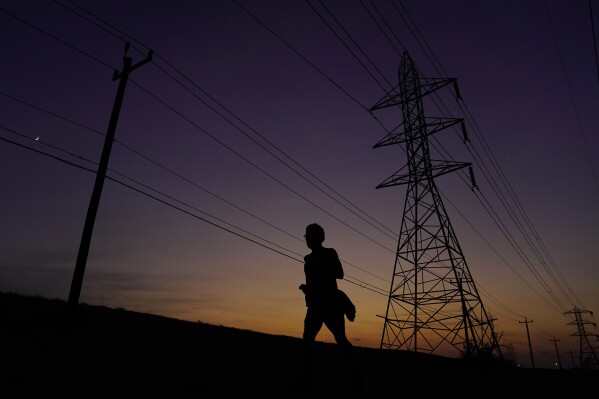 A jogger passes power lines during a sunset run, Sunday, Aug. 20, 2023, in San Antonio. Triple digit temperatures continue to stress the power grid. (AP Photo/Eric Gay)