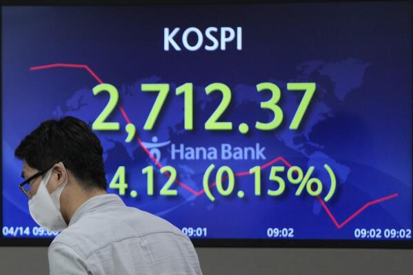 A currency trader walks by the screen showing the Korea Composite Stock Price Index (KOSPI) at a foreign exchange dealing room in Seoul, South Korea, Thursday, April 14, 2022. Asian shares were mostly higher Thursday after an advance on Wall Street that ended a three-day losing streak. (AP Photo/Lee Jin-man)