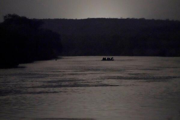 Migrants are taken across the Rio Grande on a raft at the U.S.-Mexico border, near Roma, Texas, in the early morning of March 24, 2021. (AP Photo/Julio Cortez)
