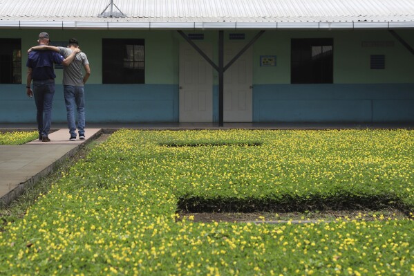 American Pastor Kenton Moody, left, walks arm in arm with a young man who was in prison for belonging to a gang, during a break on the grounds of the “Vida Libre” or “free life,” rehabilitation center, in Santa Ana, El Salvador, Saturday, April 29, 2023. The gang rehabilitation program was founded in El Salvador in 2021 by Moody. (AP Photo/Salvador Melendez)