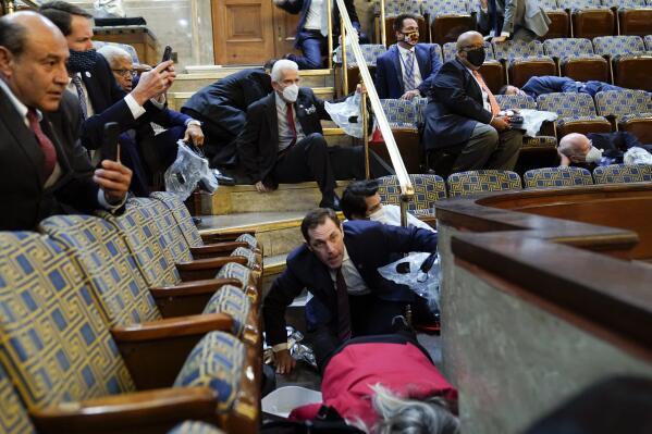 FILE - In this Jan. 6, 2021, file photo, people shelter in the House chamber as rioters try to break into the House Chamber at the U.S. Capitol in Washington. (AP Photo/Andrew Harnik, File)
