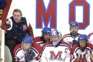 FILE - Bill Belisle, left, stands behind the bench with some of his players at a Mount St. Charles High School hockey game in Woonsocket, R.I., Dec. 28, 2001. Belisle, the Rhode Island hockey coach who led Mount Saint Charles Academy to 32 state championships in more than four decades at the helm and had more than 20 players drafted by NHL teams, died Wednesday, Jan. 12, 2022, according to the school. He was 92. (AP Photo/Robert E. Klein, File)
