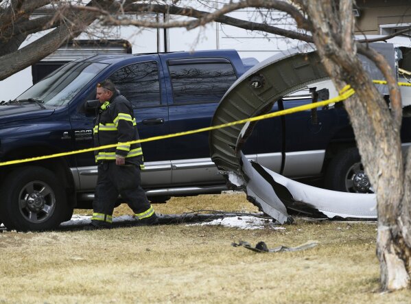 A North Metro firefighter walks past a large piece of an airplane engine in the front yard of a home on Elmwood Street near E. 13th Avenue, Saturday, Feb. 20, 2021, in Broomfield, Colo. Debris from a United Airlines plane fell onto Denver suburbs during an emergency landing Saturday after one of its engines suffered a catastrophic failure and rained pieces of the engine casing on a neighborhood where it narrowly missed a home. (Andy Cross/The Denver Post via AP)