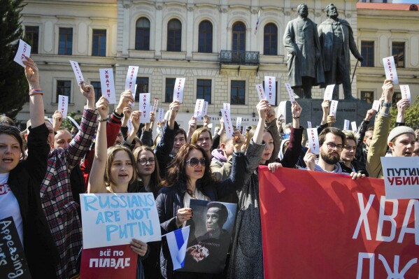 People hold sheets reading "enough" as they protest in downtown Tbilisi, Georgia, Sunday, March 17, 2024. Russians at home and abroad are heading to the polls for a presidential election that is all but certain to extend President Vladimir Putin's rule after he clamped down on dissent. (AP Photo/Nicolo Vincenzo Malvestuto)