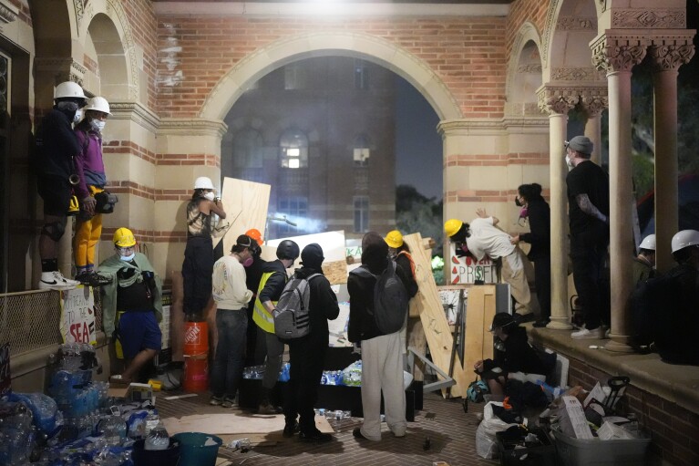 Pro-Palestinian demonstrators watch police activity behind makeshift barricades on the UCLA campus on Wednesday, May 1, 2024, in Los Angeles.  (AP Photo/Jae C. Hong)